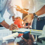 Contractor and engineer with blueprints discuss at a modern construction site, Engineers in mechanical factory reading instructions