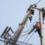 Selective focus of electricians are fixing power transmission line on a electricity pole